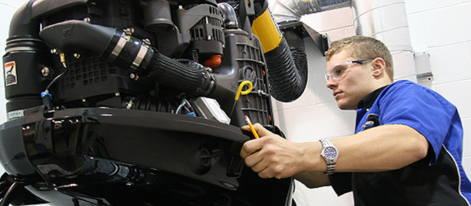 Man in blue and black shirt working on repairing boat machinery.