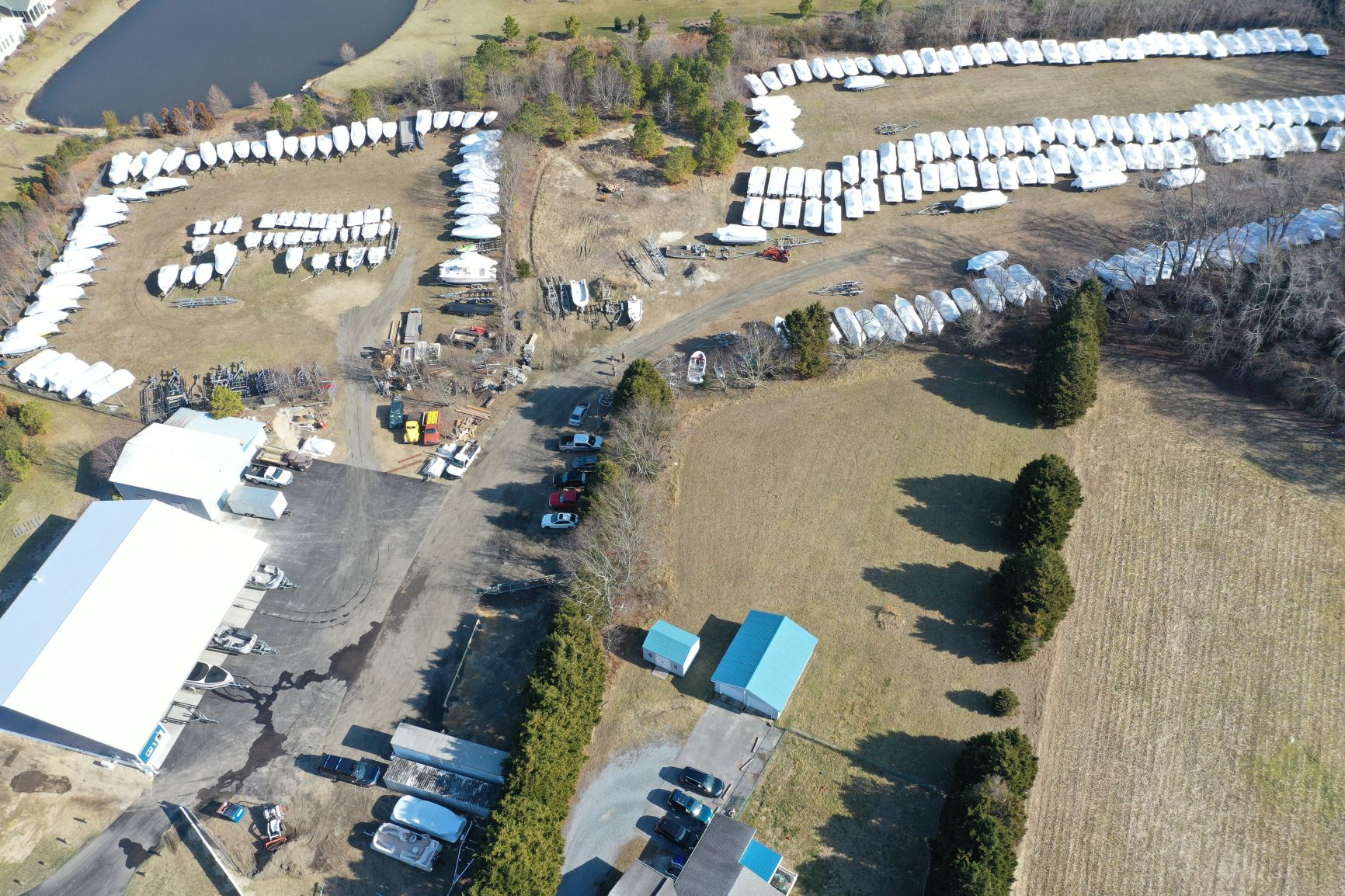 Numerous buildings, trees, and parking lots with boats on display.